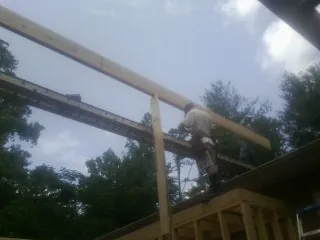 Carpenter setting a ridge beam over a new addition frame — Ice Dam Removal by Roofing Brothers in Fairport