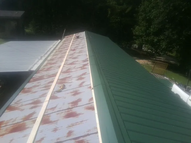 Old rusted panels beside newly installed green metal roofing — Wind Damage Roof Repair by Roofing Brothers in Fairport