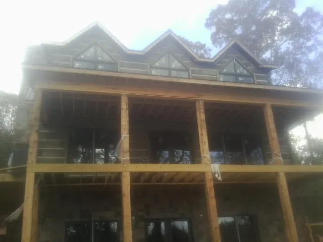 Dormers and porch framing on a large log home under construction — Roof Coating work by our crew in Fairport