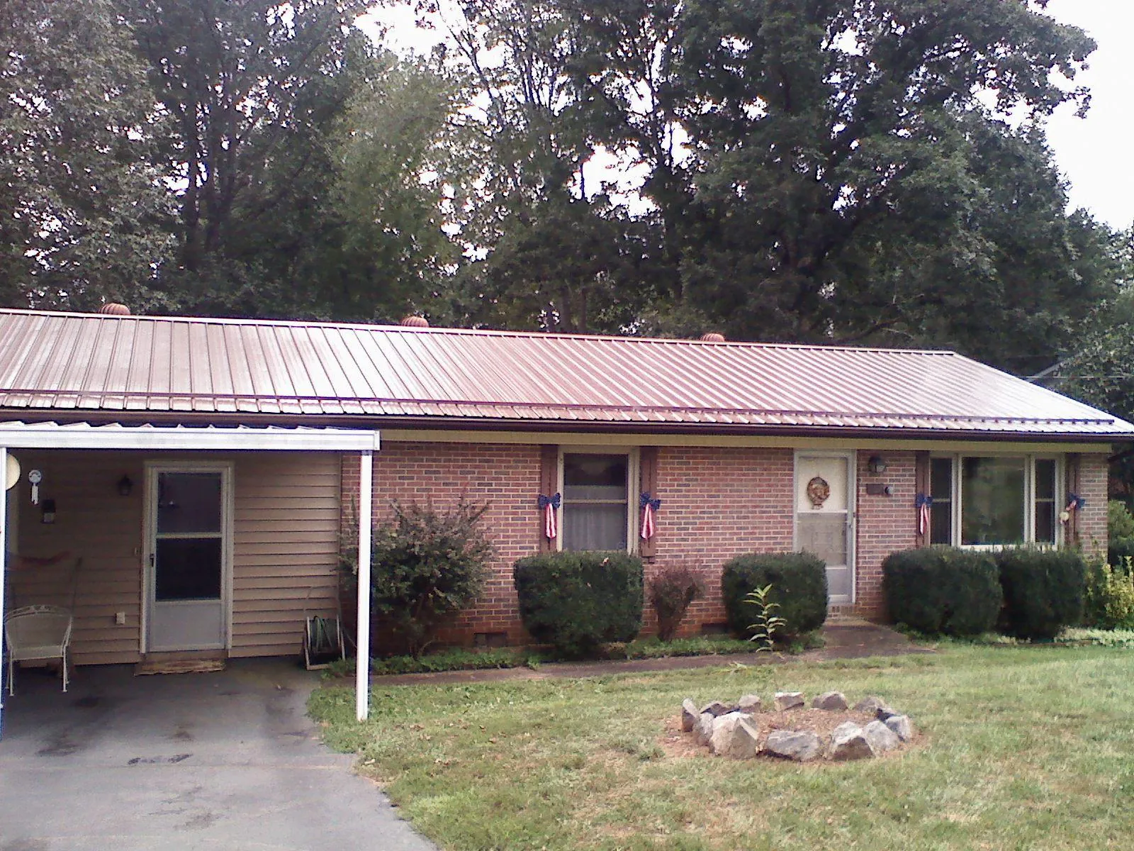 Bronze metal roof and carport on a brick ranch home — Roof Repair work by our crew in Fairport