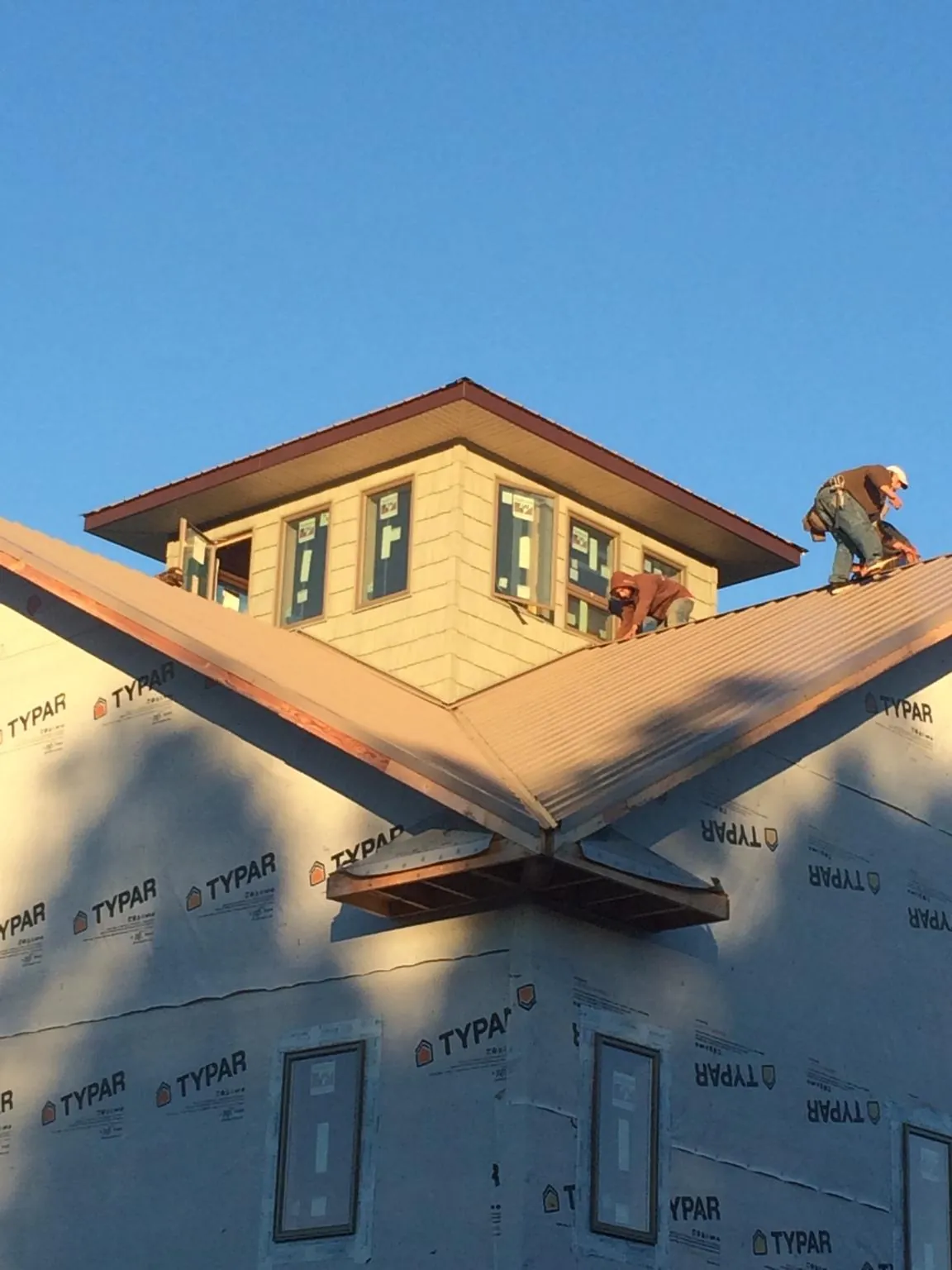 Roofers working around a rooftop cupola on a new metal roof at sunset — Roof Waterproofing in Fairport by Roofing Brothers